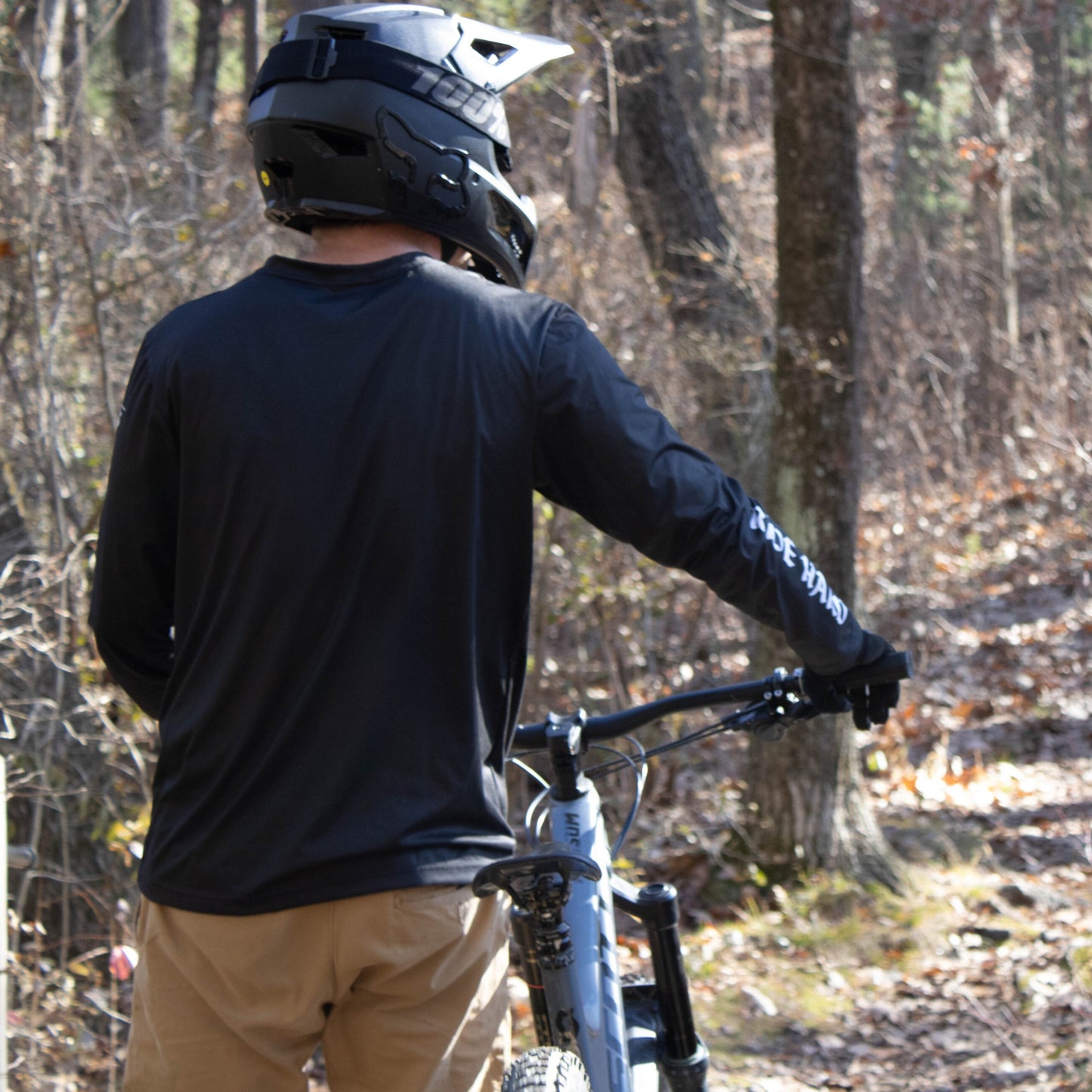 Mountain biker in black long sleeve MTB jersey walking with mountain bike